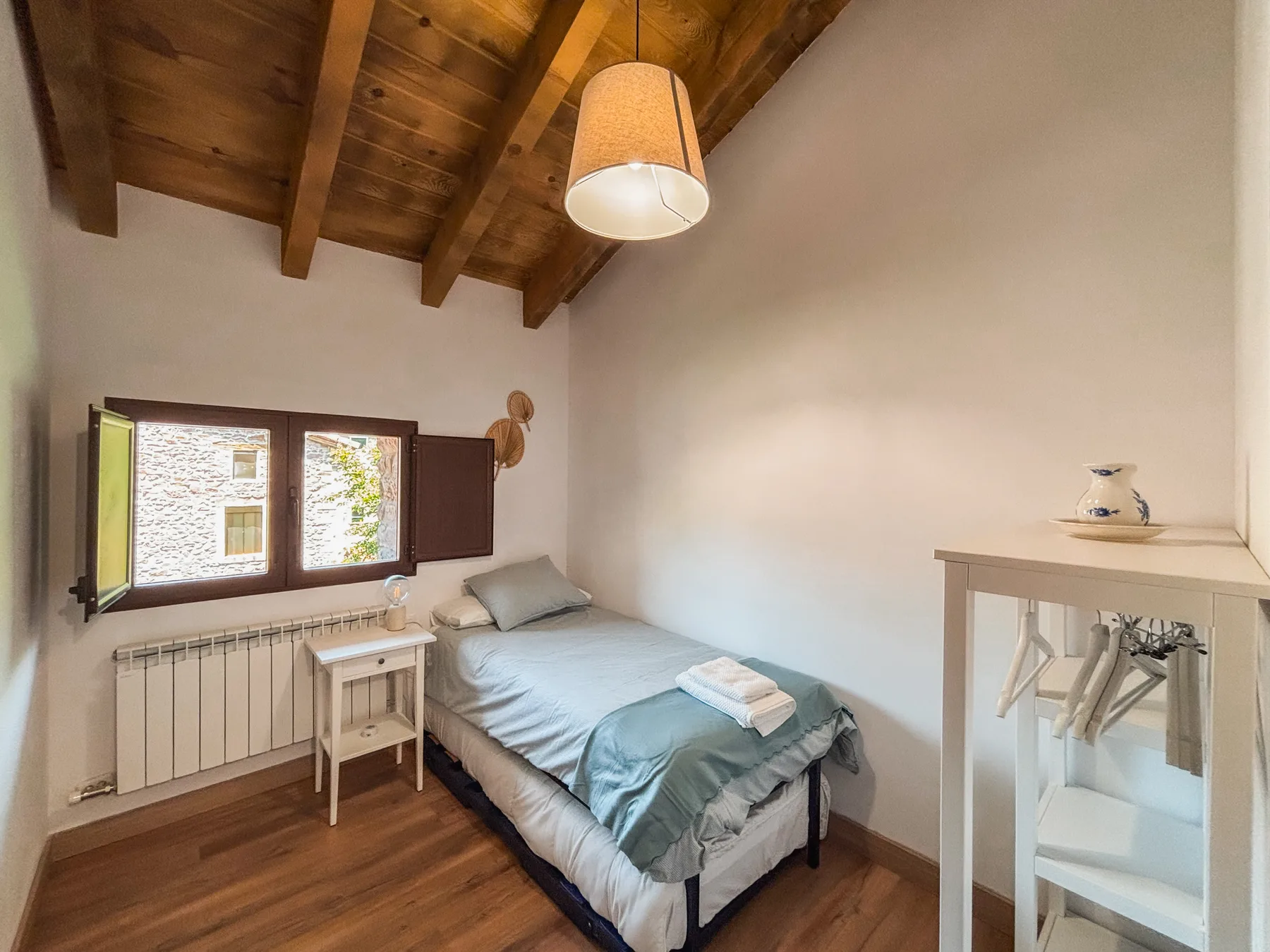 Dormitorio individual con cama azul y vigas