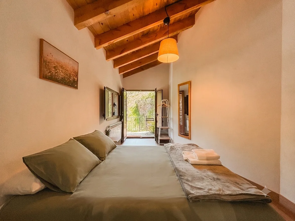 Dormitorio principal con ropa verde y puerta al balcón